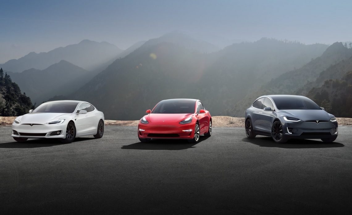 Tre modelli di Tesla in bianco, rosso e blu con delle montagne sullo sfondo
