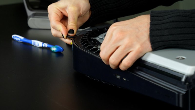 Usate un plettro per rimuovere la presa di aereazione che blocca la ventola di PS5