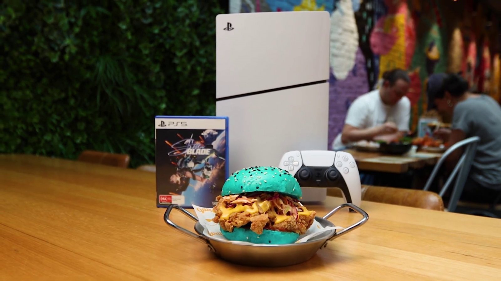 Il burger di Stellar Blade di fronte a una PS5 Slim e un controller DualSense