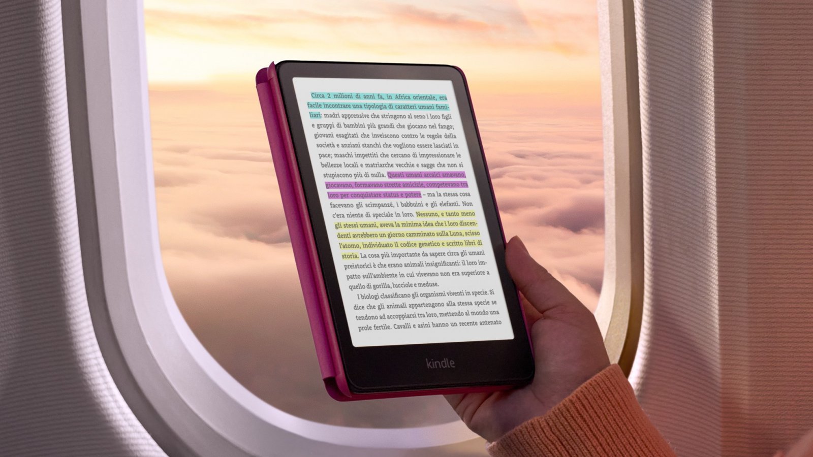 Un kindle tenuto in mano di fronte all'oblo di un aereo