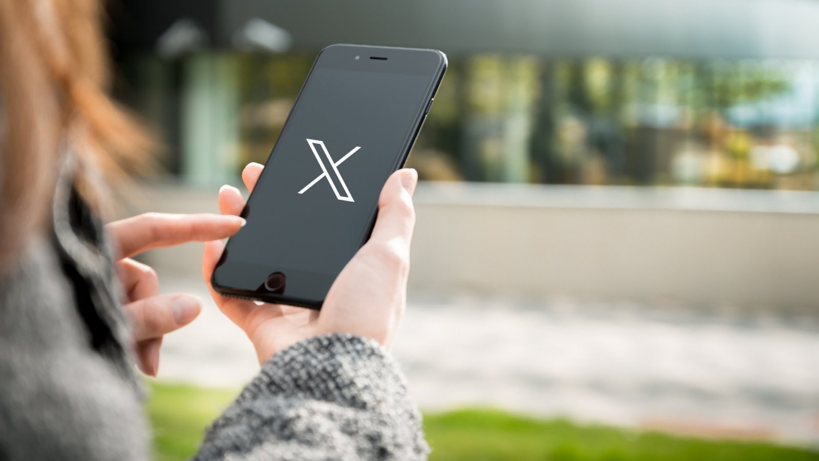 Una ragazza con lo smartphone e il logo di X