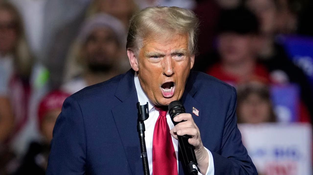 Trump con la bocca aperta mentre tiene in mano un microfono